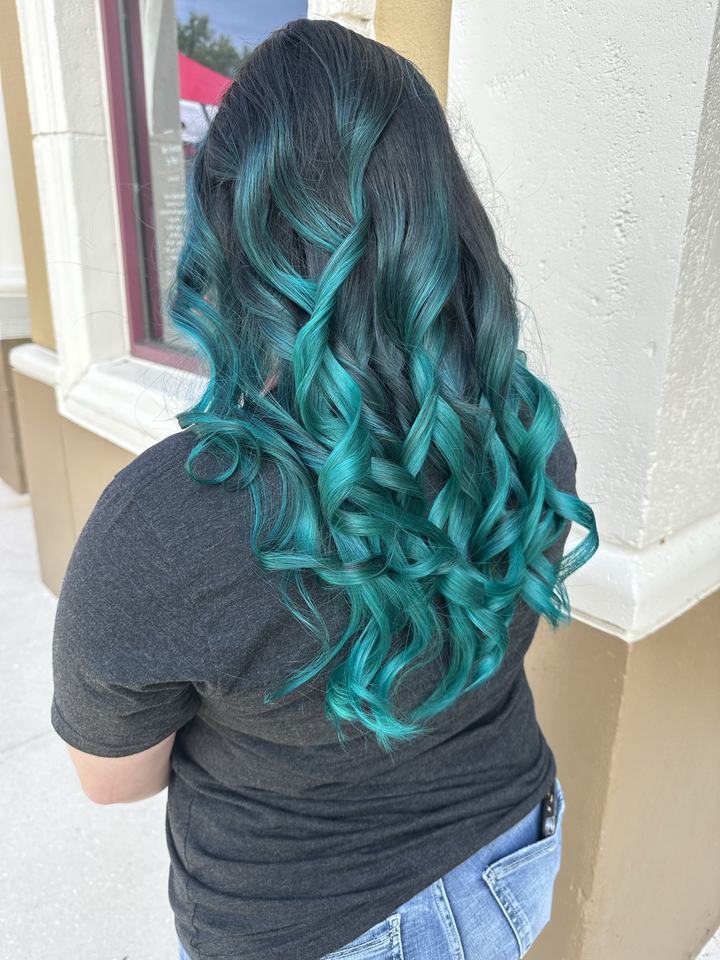 Long teal curls on dark hair, seen from behind